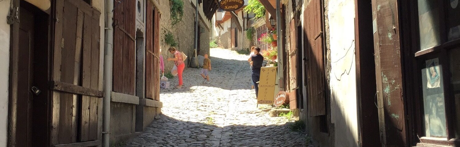 Una calle adoquinada en un pueblo histórico con edificios tradicionales y un letrero que dice 'Sofranpolka Xonagi'.