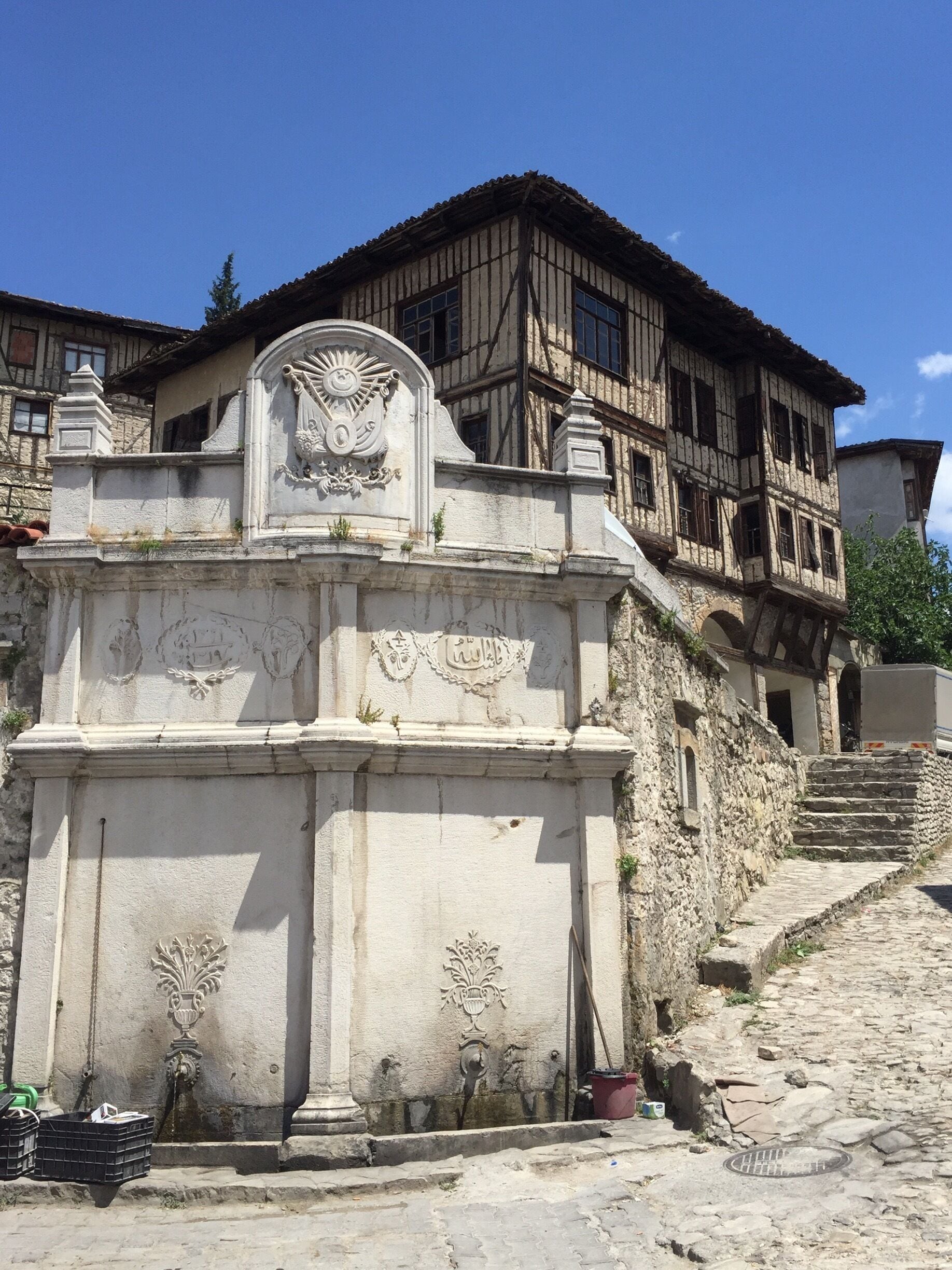 Um edifício histórico com fachada de pedra, um brasão decorativo e uma escadaria que leva à entrada.