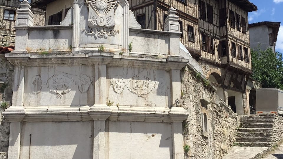 Um edifício histórico com fachada de pedra, um brasão decorativo e uma escadaria que leva à entrada.