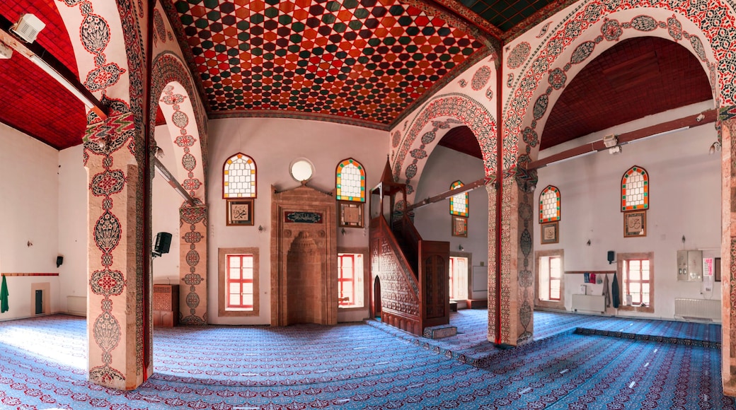 An interior with ornate arches, patterned carpet, and stained glass windows.