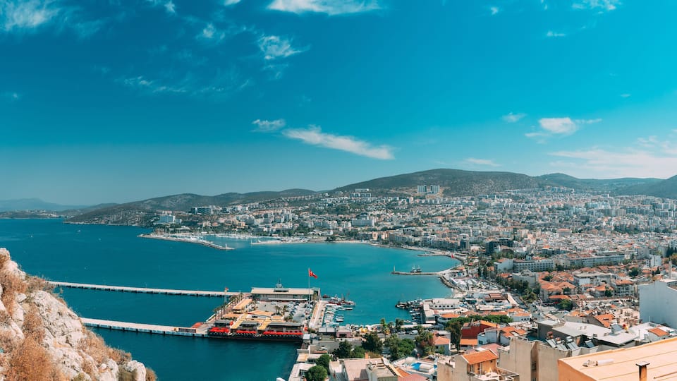 Kusadasi, Aydin, Aydın Province, Turkey. Waterfront And Kusadasi Cityscape In Sunny Summer Day. Scenic View Of Kusadasi Skyline At Aegean Coast, Turkey. Panorama, Panoramic View