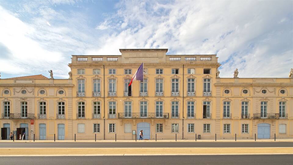 A historic building with a large flag, ornate balconies, and a clear sky.