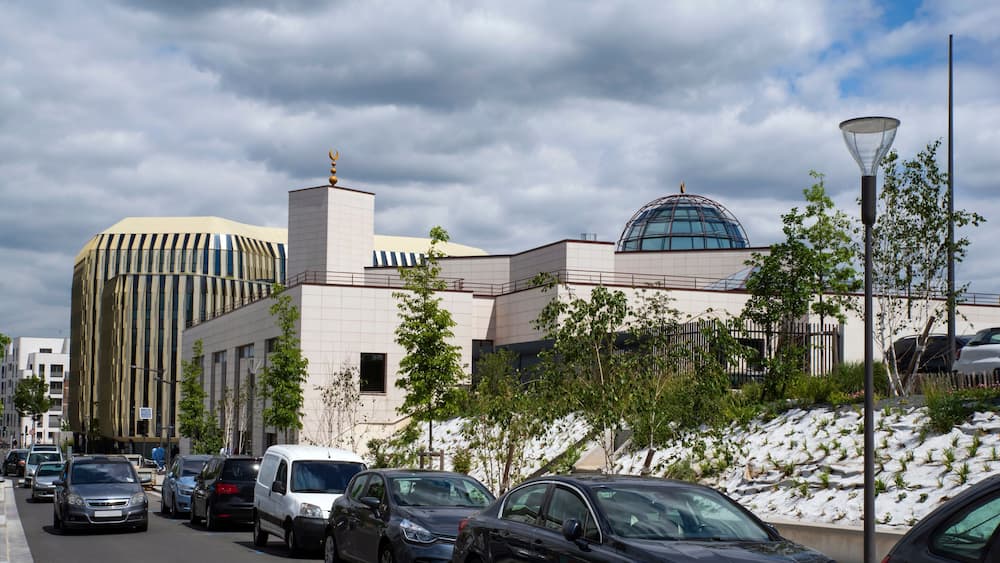 A modern building with a dome and a tall, striped structure.