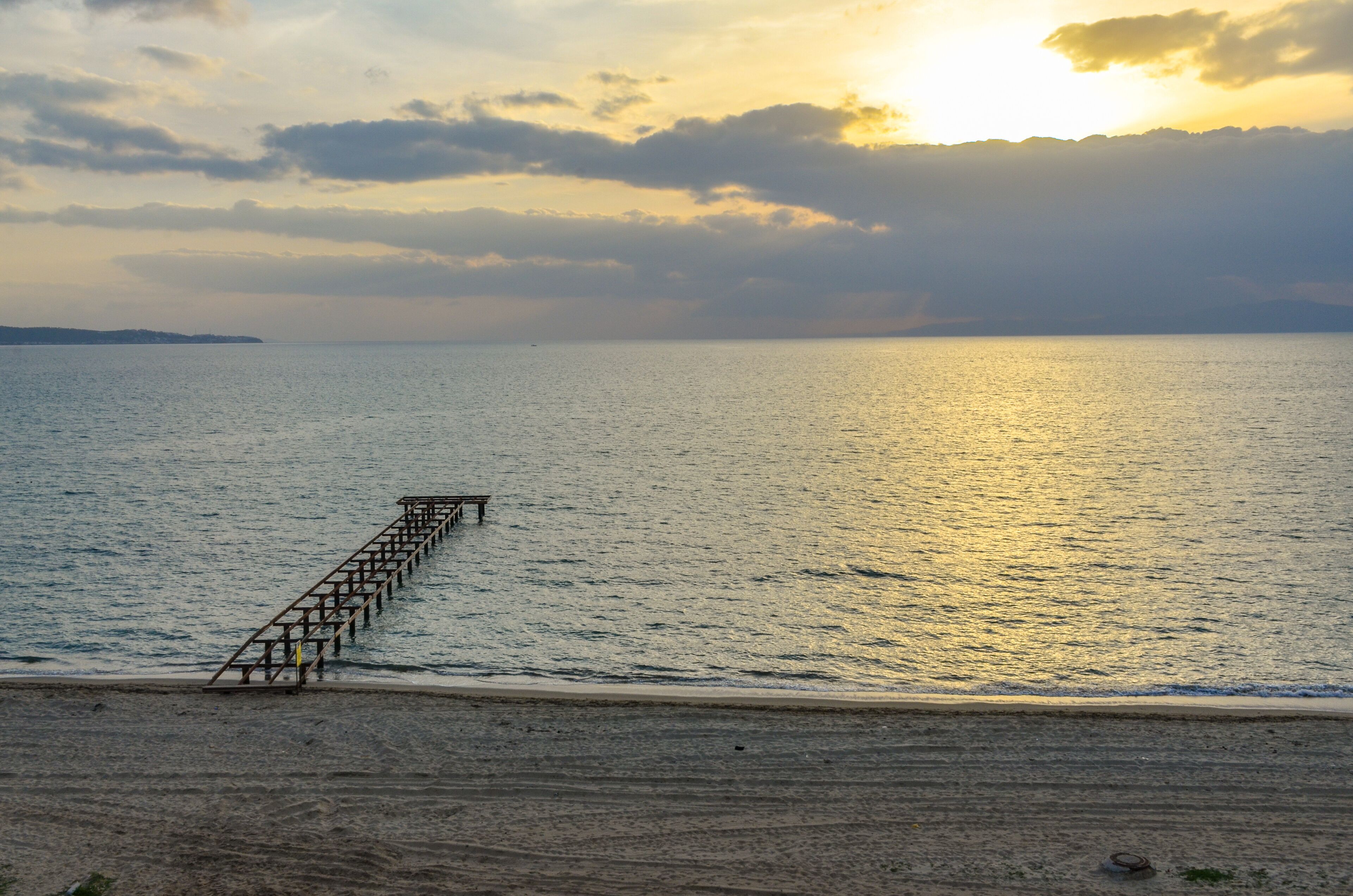 A pier extending into calm waters during sunset.