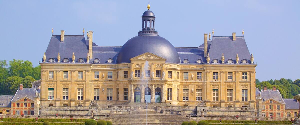 A large, historic building with a prominent dome and multiple chimneys.