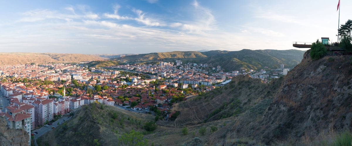 A city nestled in a valley with a prominent cliffside and a distant mountain range.