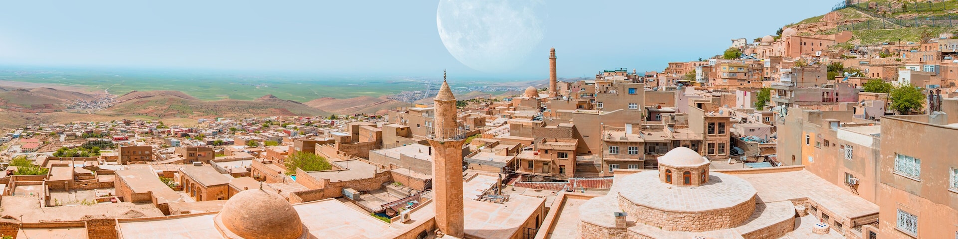 A cityscape with a prominent mosque, a large dome, and a mountain in the background.