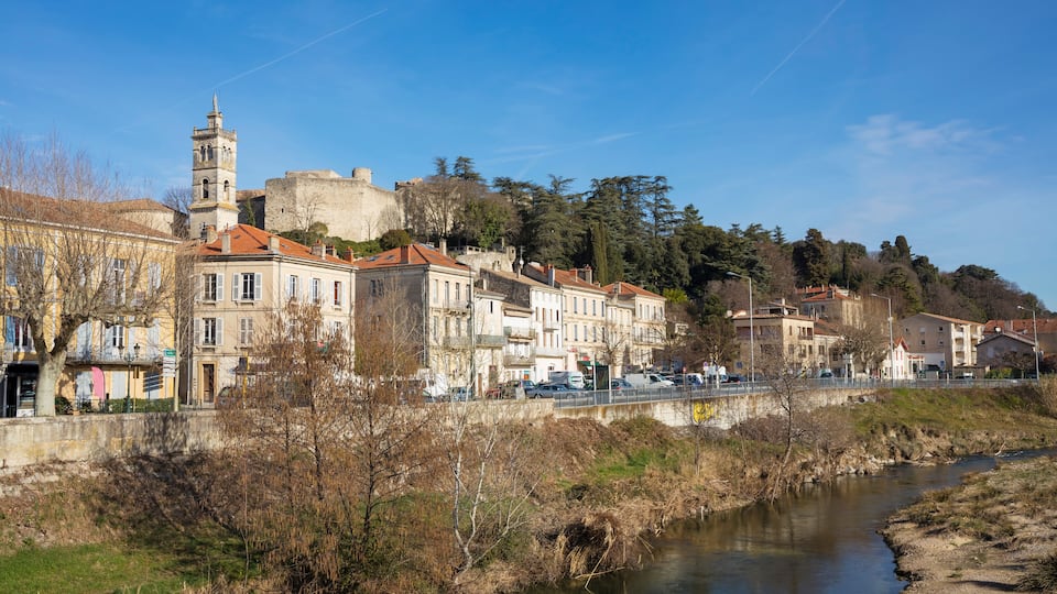 A river flowing through a town with historic buildings and a tower.