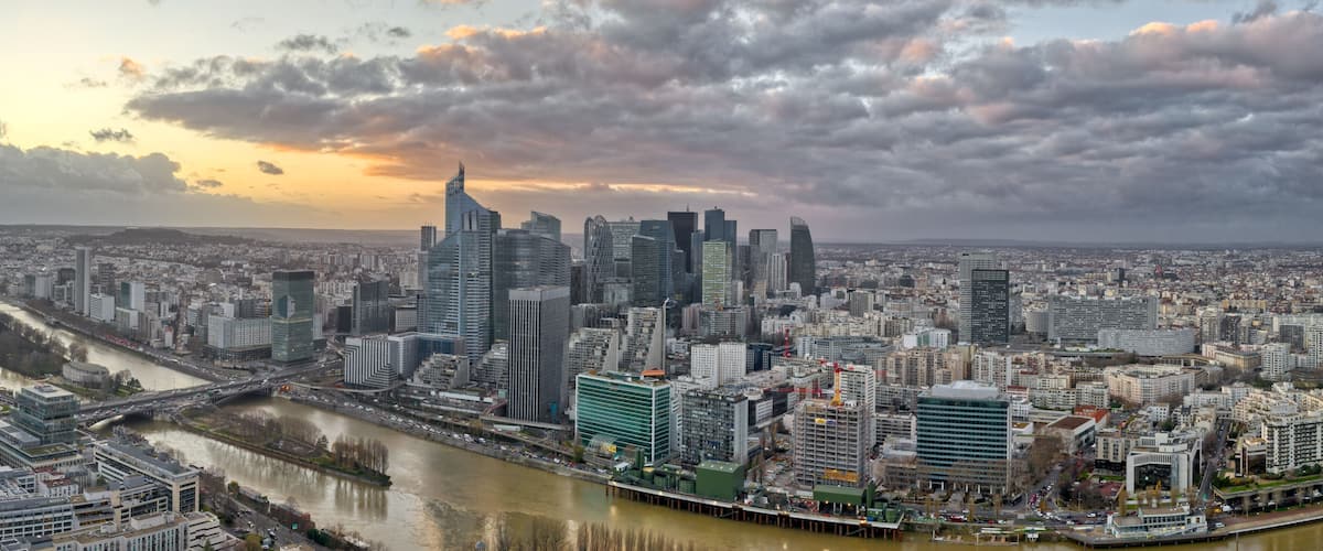 A cityscape with a river, modern skyscrapers, and a cloudy sky.