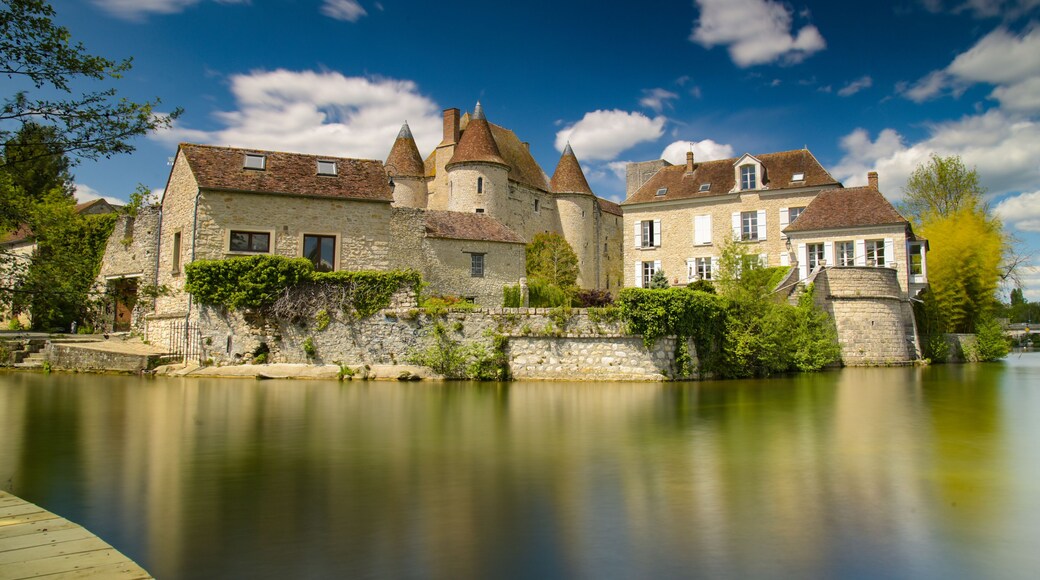 A historic stone castle by a calm river with a wooden dock.