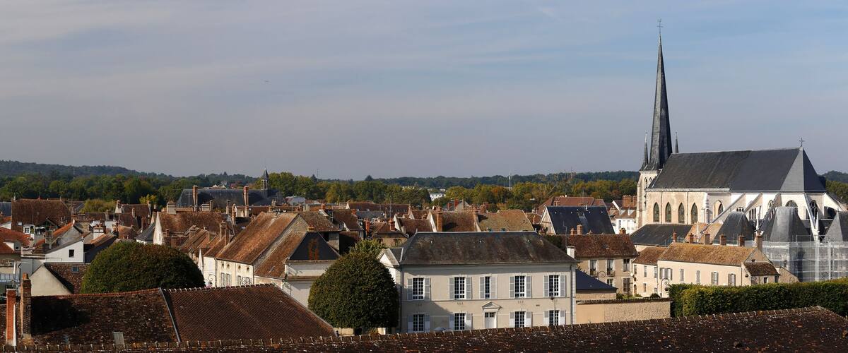 A historic town with stone buildings, a prominent church spire, and a castle-like structure.
