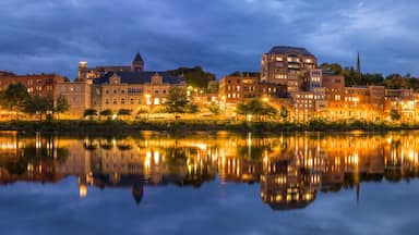 A cityscape at dusk with buildings reflecting on a calm river.
