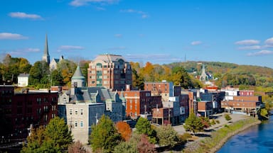 A riverside town with historic buildings, a church steeple, and autumn foliage.