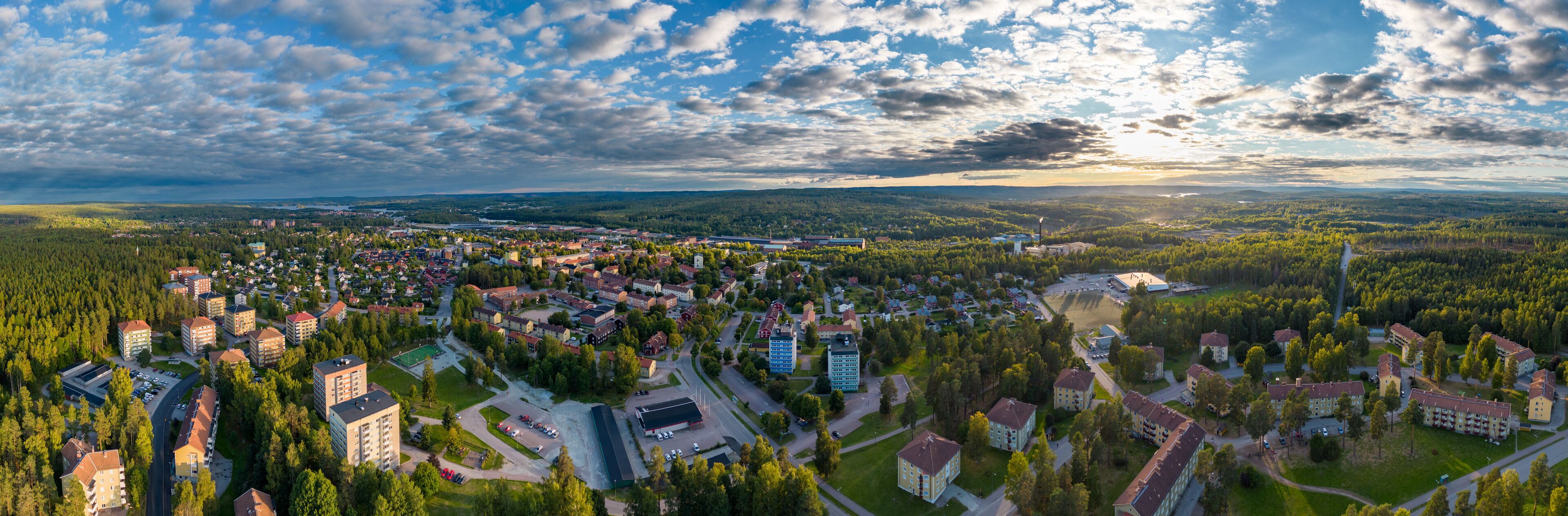 An aerial view of a town surrounded by dense forests, with a mix of residential and commercial buildings.