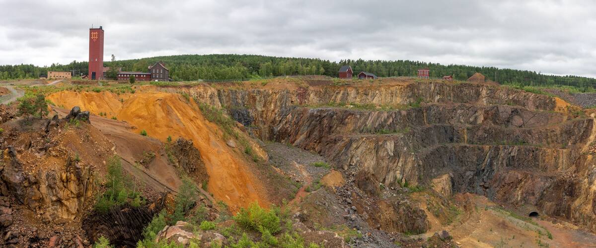 A mining site with large open pits and a red building.