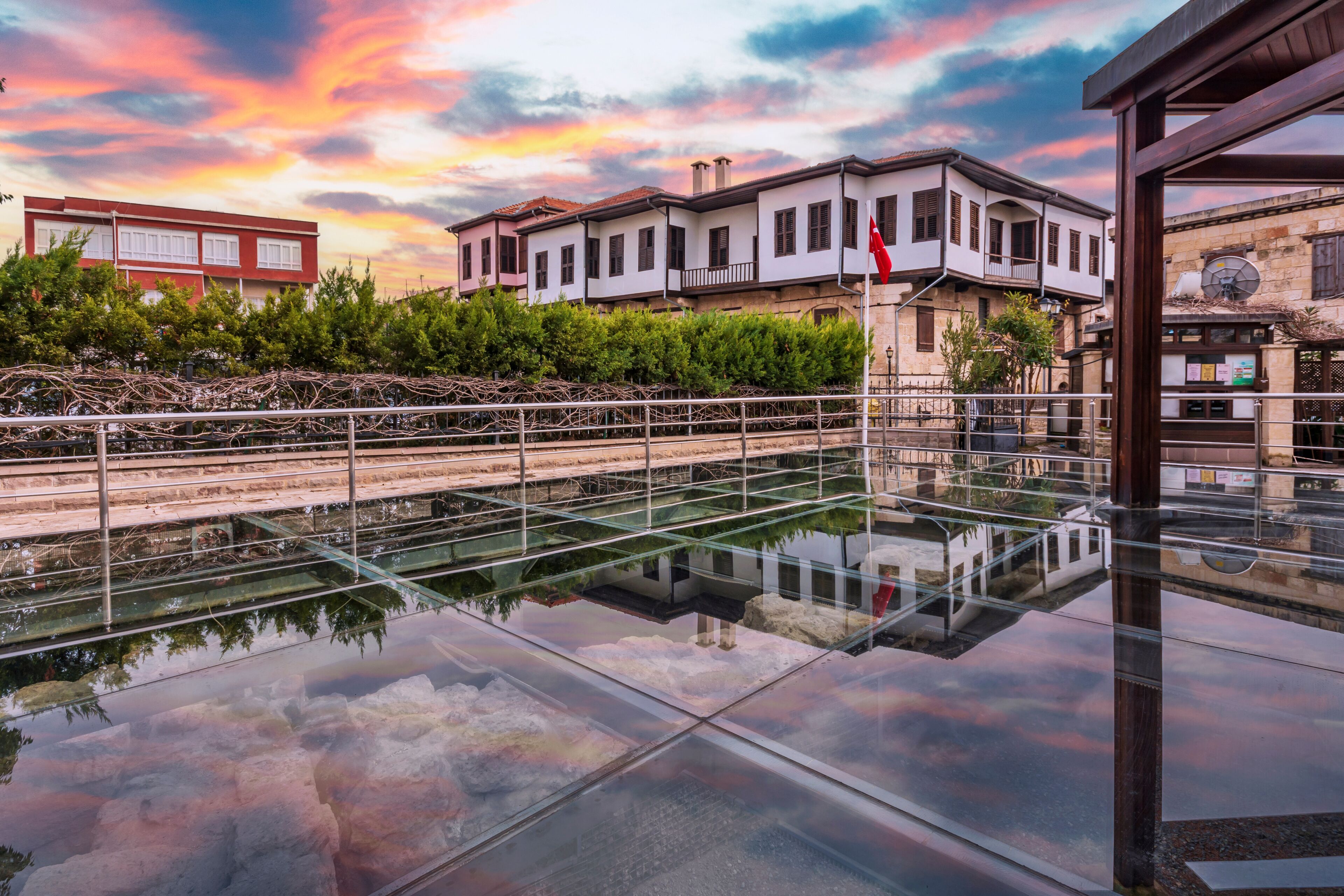 Un paseo marítimo con suelo de vidrio que refleja los edificios y el cielo.