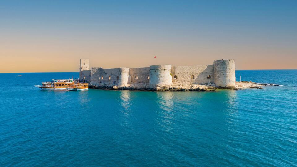 A coastal castle surrounded by turquoise waters.
