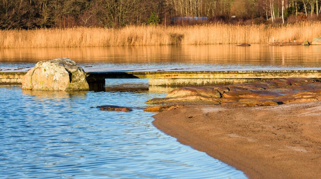 Sandy beach with wooden pier and granite boulder in the water. Location Nattraby, Karlskrona, Sweden.