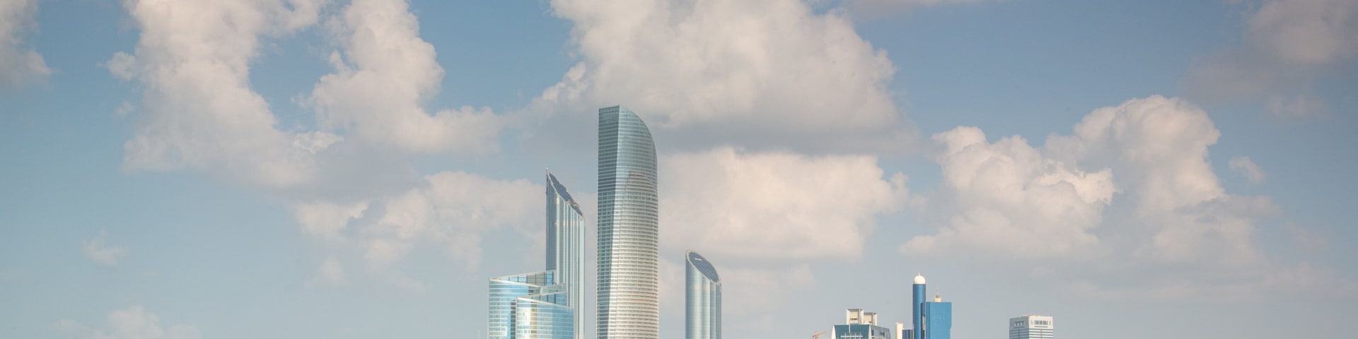 A coastal city skyline with modern skyscrapers and a clear blue sky.