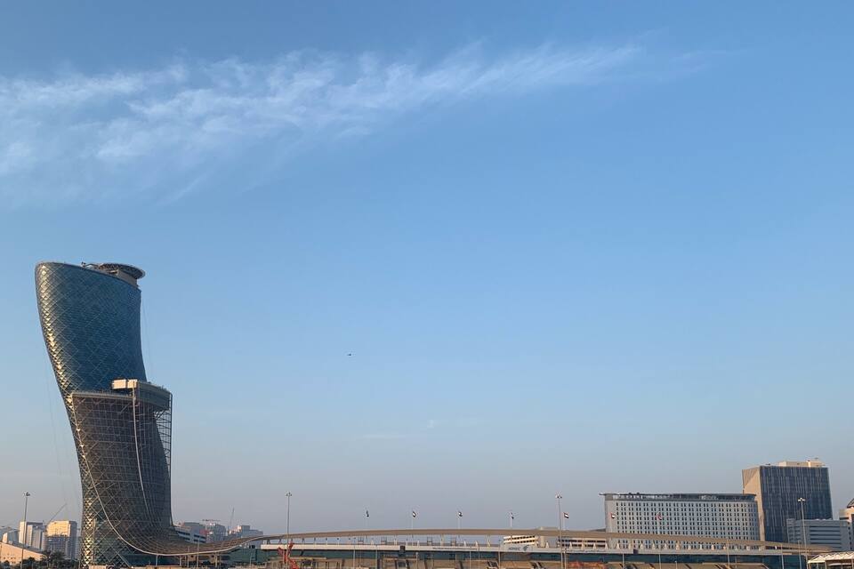 A modern cityscape with a distinctive curved skyscraper and a bridge.