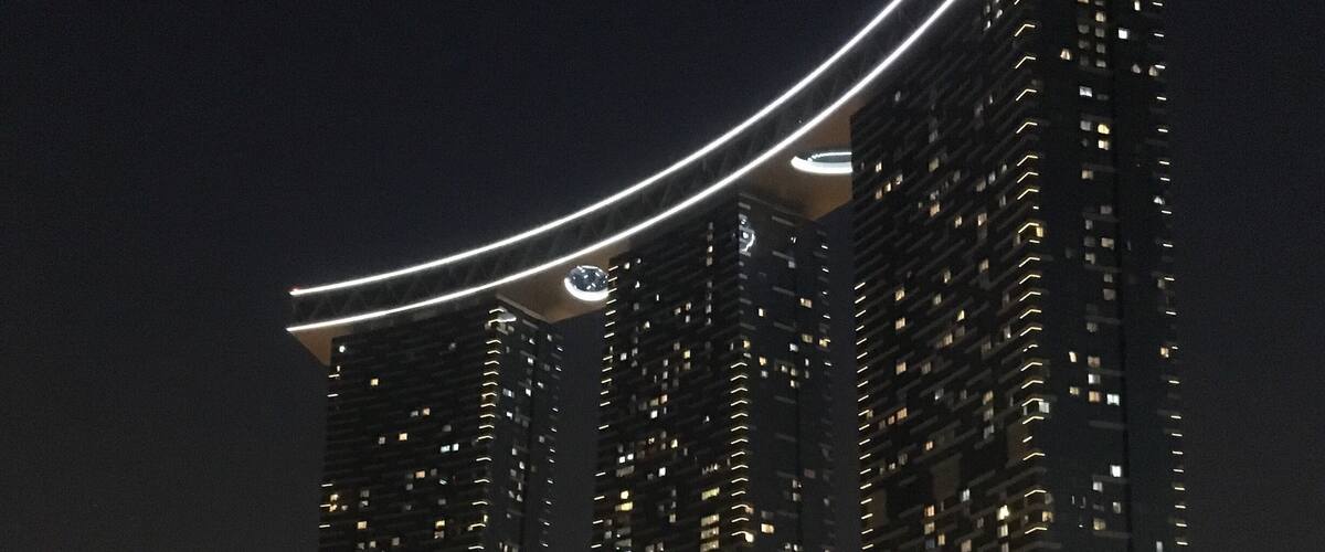 A high-rise building with a distinctive curved light feature at the top.