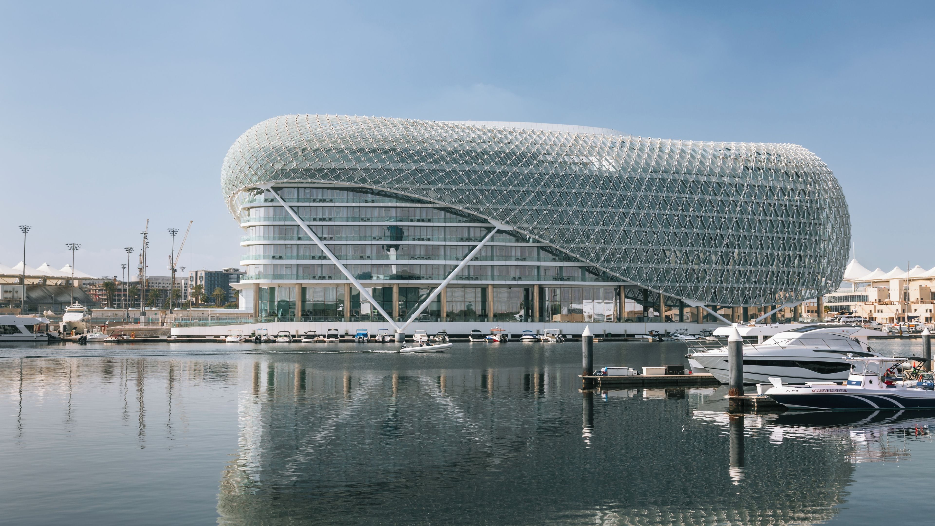 A modern architectural building with a unique spherical design, situated by a marina with boats docked.