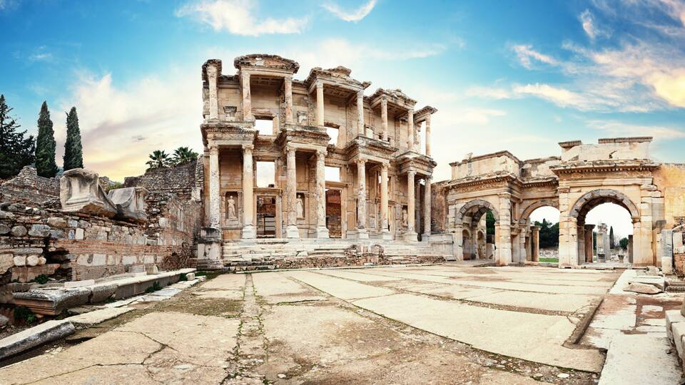Ancient ruins with columns and arches, including a large central structure and smaller surrounding buildings.