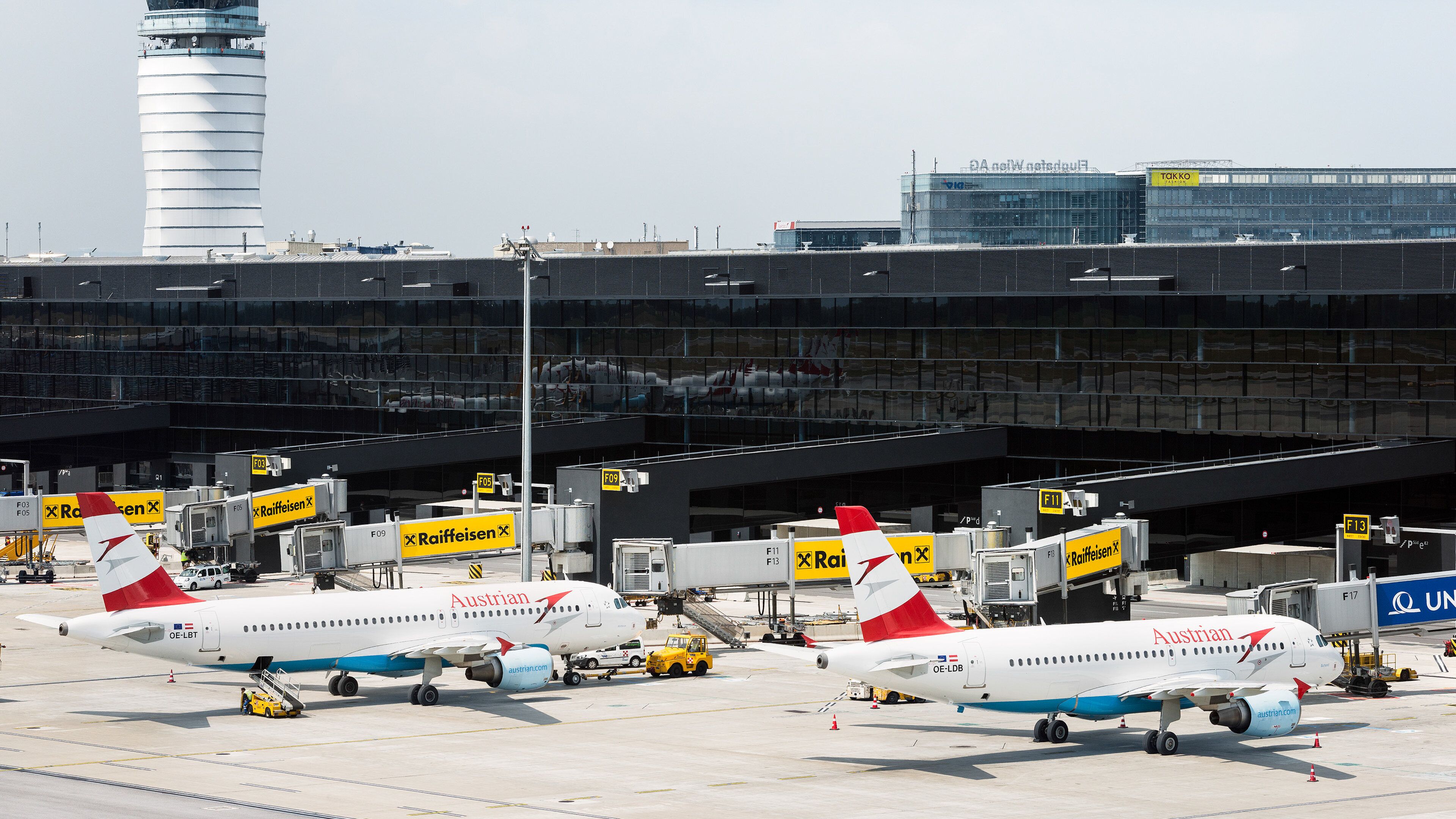 An airport tarmac with multiple Austrian Airlines aircraft parked at gates.