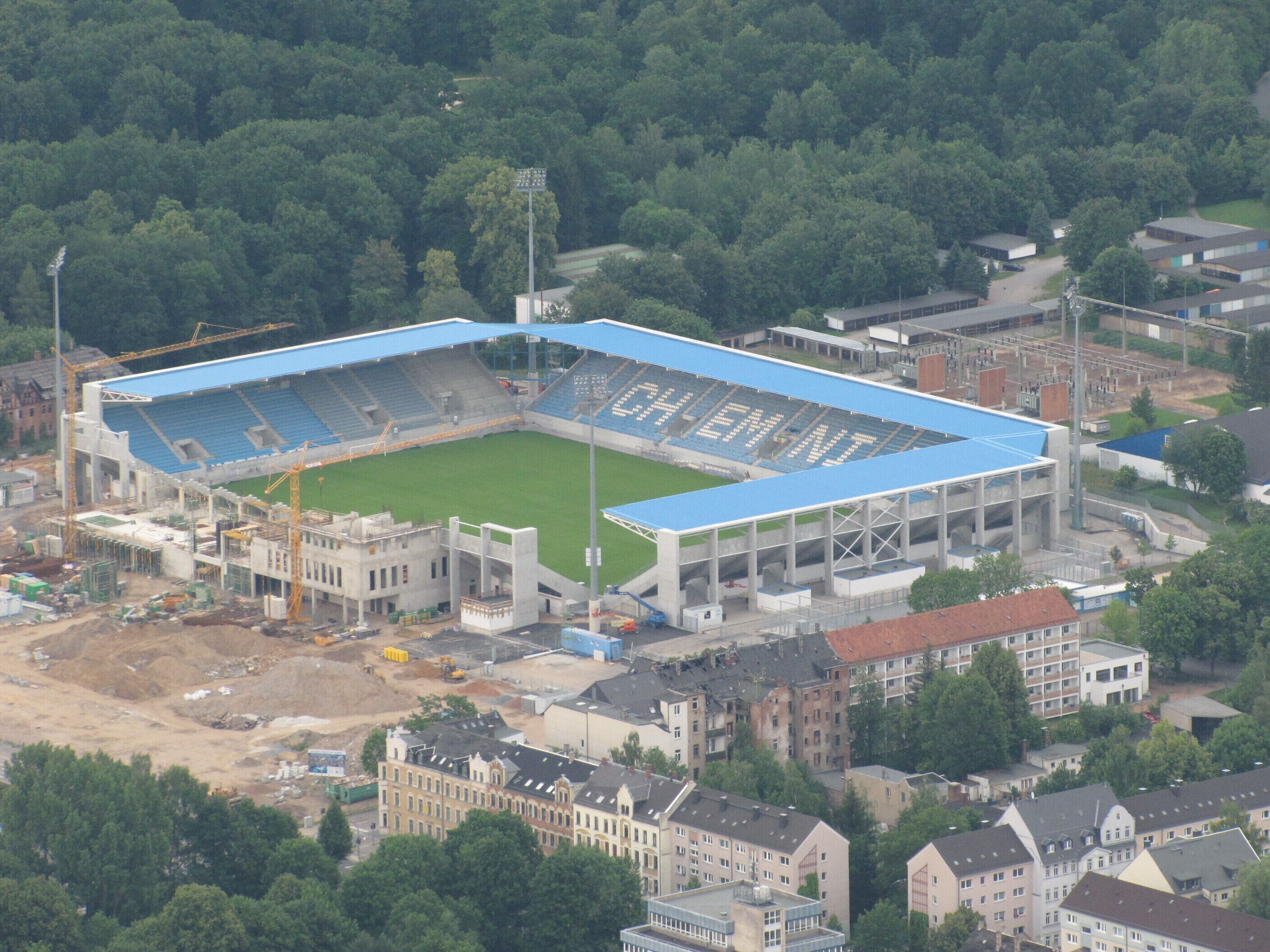 An aerial view of a stadium under construction surrounded by buildings and trees.