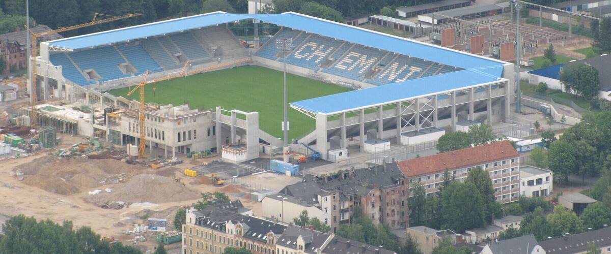 An aerial view of a stadium under construction surrounded by buildings and trees.