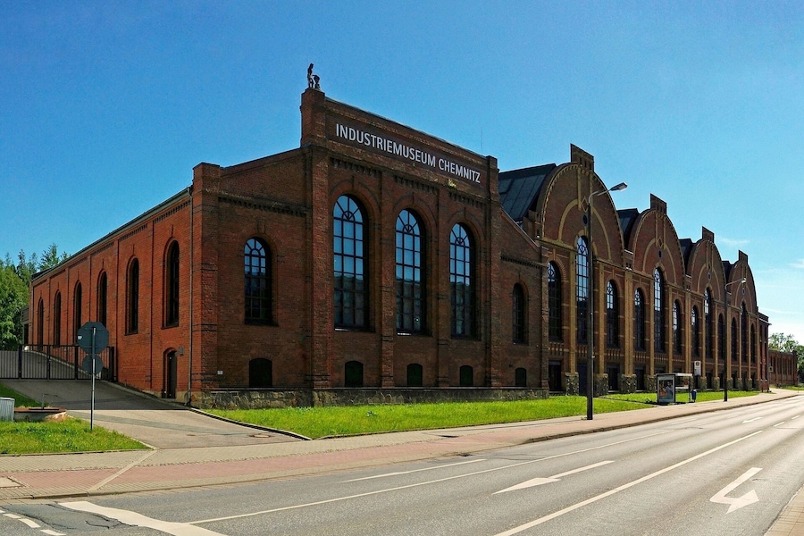 A large brick building with arched windows and a sign that reads "INDUSTRIEMUSEUM CHEMNITZ".