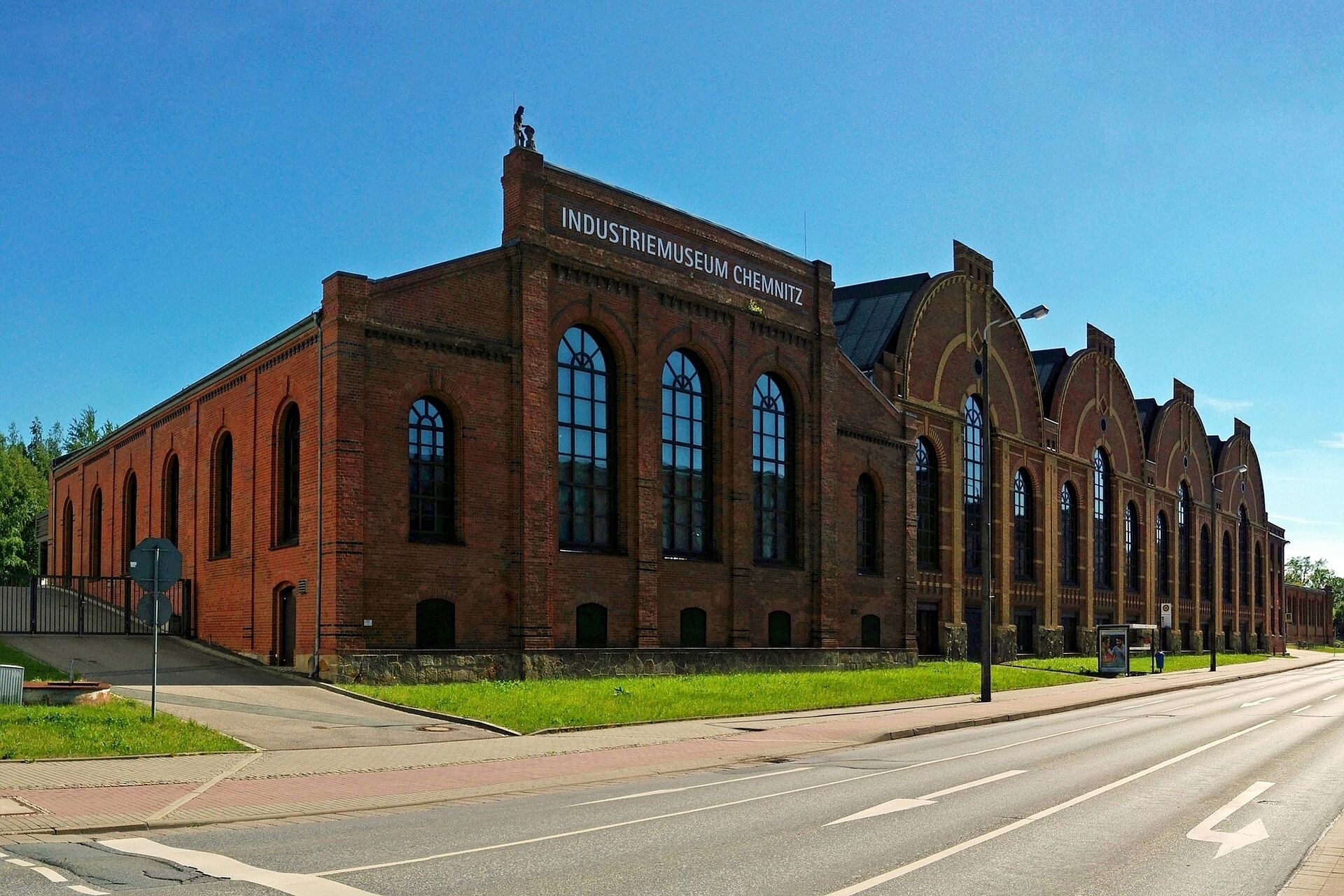 A large brick building with arched windows and a sign that reads "INDUSTRIEMUSEUM CHEMNITZ".
