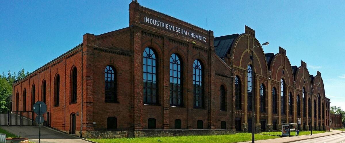 A large brick building with arched windows and a sign that reads "INDUSTRIEMUSEUM CHEMNITZ".