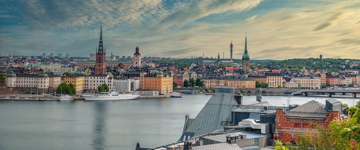 A cityscape with a river, historic buildings, and two prominent spires.
