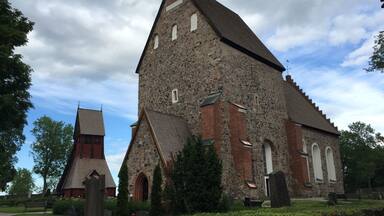 A large stone church with a steep roof and a smaller adjacent structure.