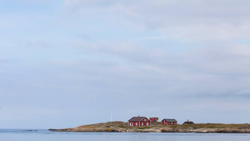 A coastal landscape with a rocky outcrop and two red houses.