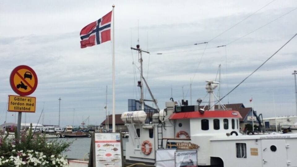 A harbor with a Norwegian flag, a no parking sign, and a boat named 'Clipper'.