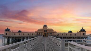 A waterfront building with domed roofs and a wooden pier leading to it.