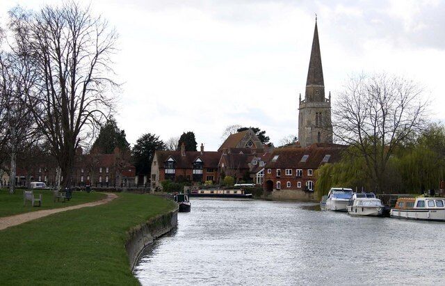 A canal with boats, a church spire, and residential buildings.