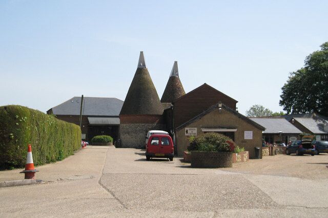 A building with conical roofs, a red car parked in front, and a clear sky.