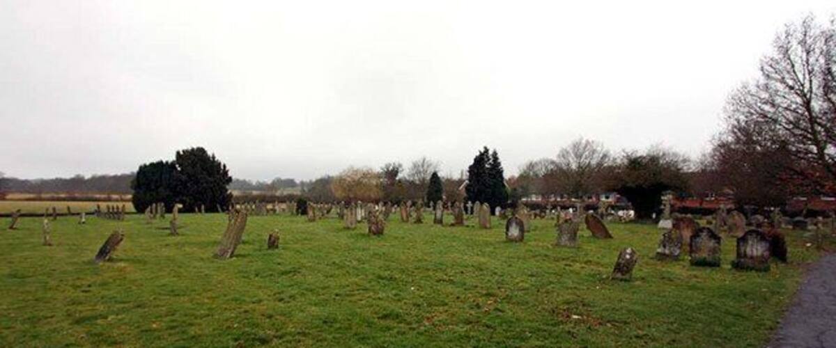 A cemetery with numerous headstones and trees.