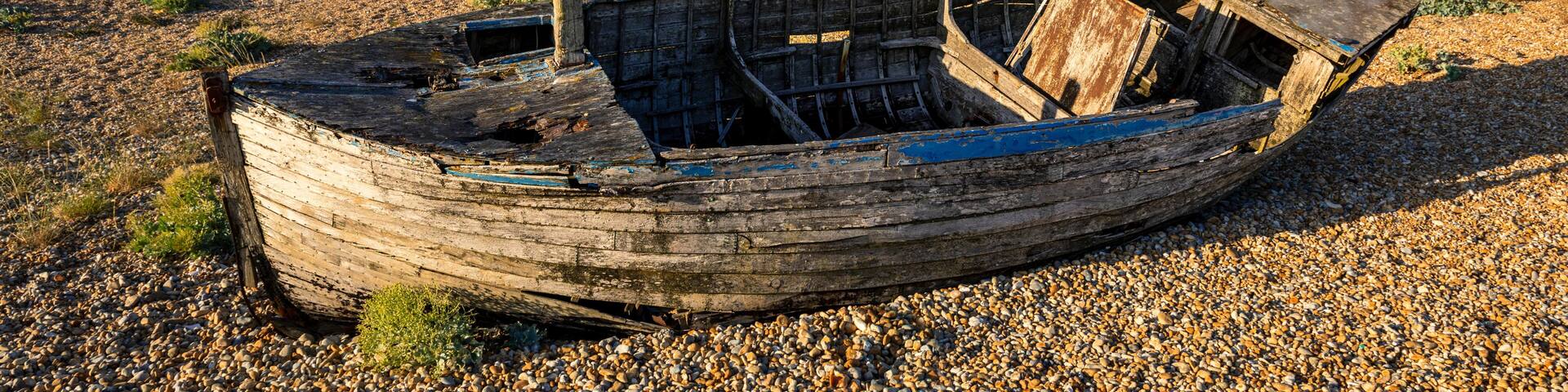 Old wrecked fishing boats on the shingle of Dungeness beach on the Kent coast south east England