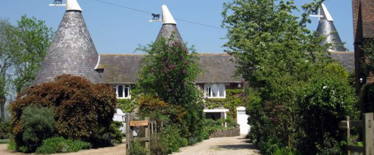 Un paysage rural caractérisé par des bâtiments traditionnels aux toits coniques, un chemin de gravier et une végétation luxuriante.