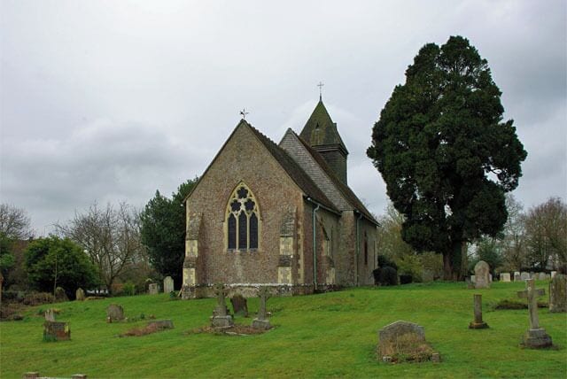 A church with a large tree in front.