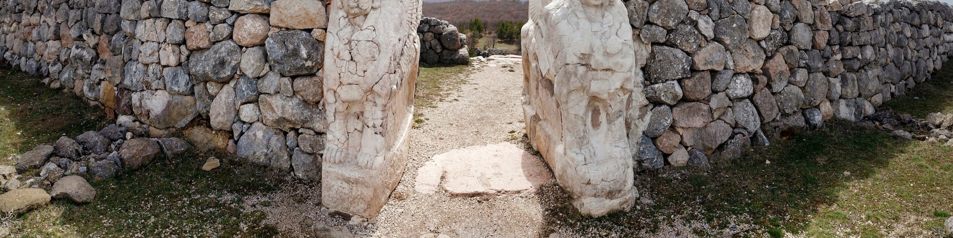 A stone wall with carved figures and a narrow path leading through it.