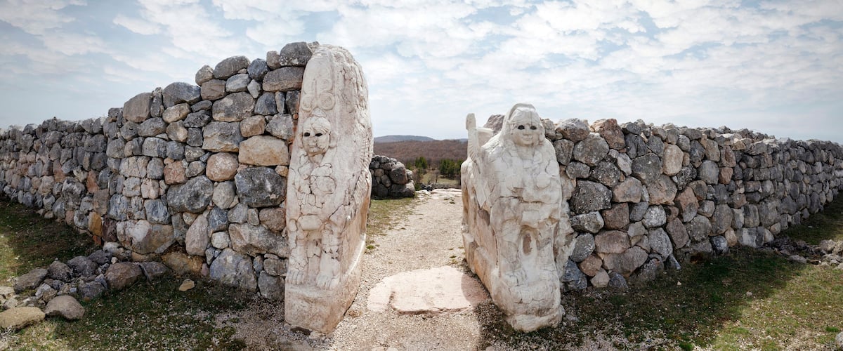 A stone wall with carved figures and a narrow path leading through it.