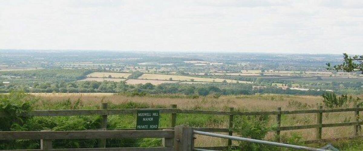 A view of the countryside from a high vantage point with a sign indicating 'Midgewell Mill, Private Road'.