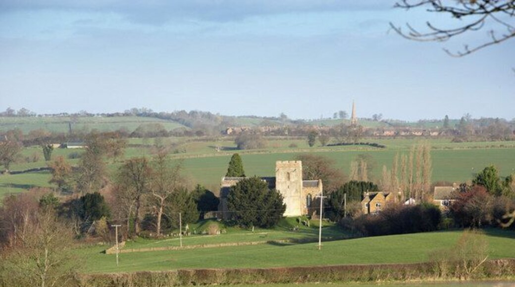Barford St Michael parish church viewed from the Nether Worton Road, with the village of Bloxham and the spire of St Mary's parish church in the distance.