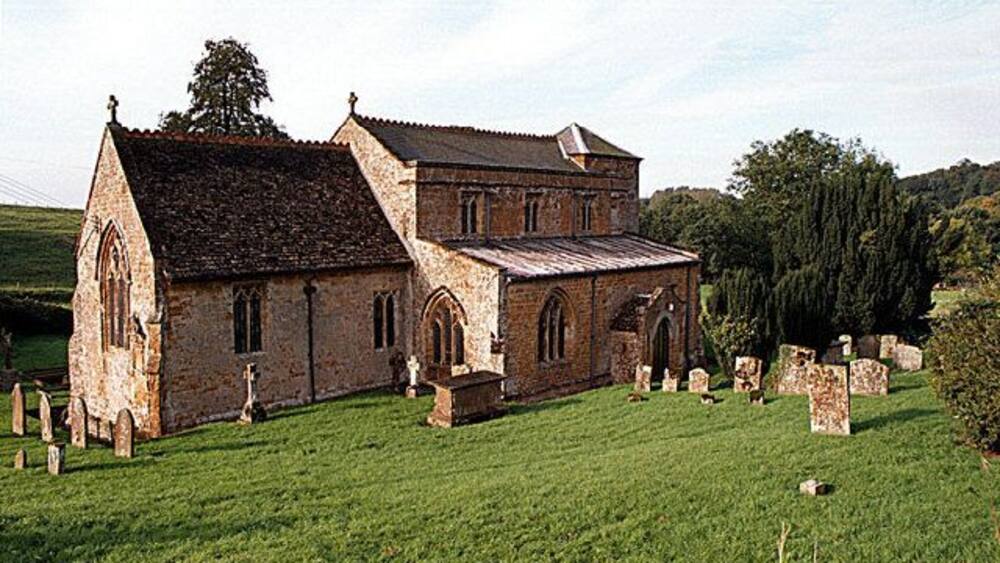 Eine historische Steinkirche mit einem grasbewachsenen Friedhof im Vordergrund.