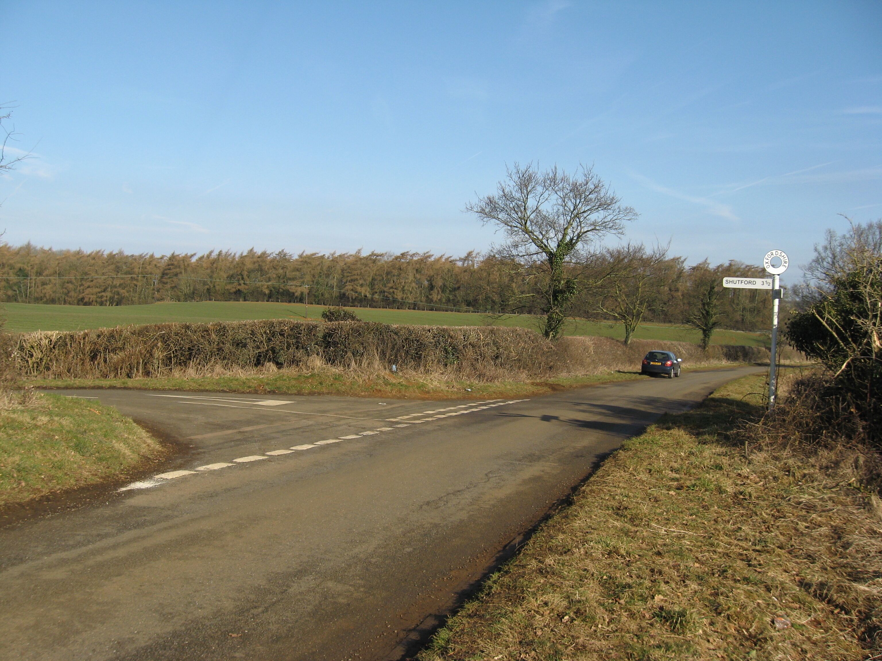 A rural road with a sign indicating Shutford 3 1/2 miles ahead.